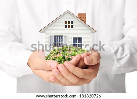 holding house representing home ownership and the Real Estate business