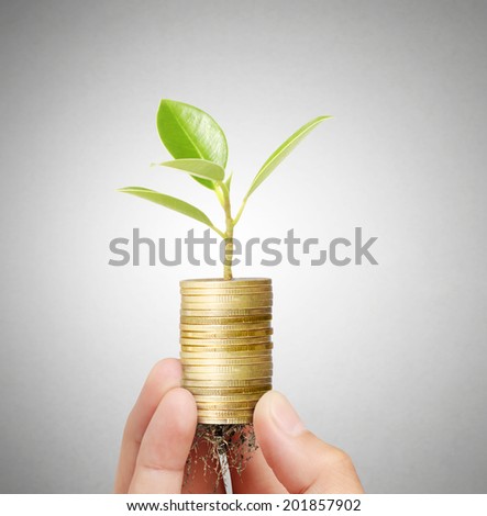 Businessman holding plant sprouting from a handful of coins