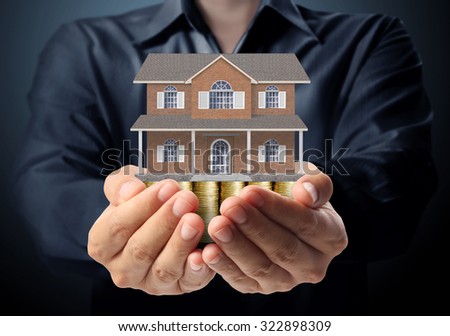 holding house representing home ownership and the Real Estate