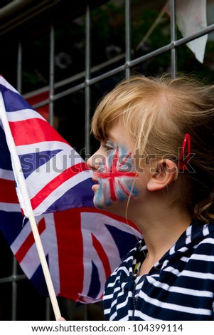 LONDON - JUNE 5: An unidentified girl with Union Jack face paint and flag waits for the carriage procession as part of the Diamond Jubilee celebrations on June 5, 2012 in London.