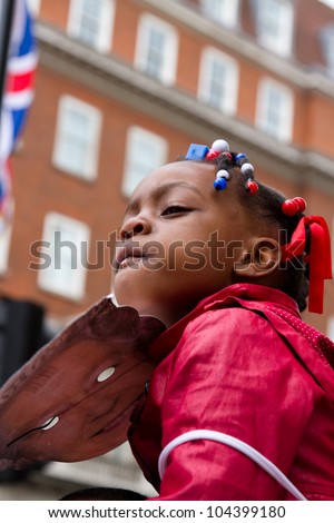 LONDON - JUNE 5: A happy unidentified girl holding a mask of the Queen waits for the carriage procession as part of the Diamond Jubilee celebrations on June 5, 2012 in London.