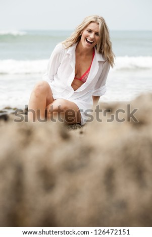 Beautiful woman sitting on rocks laughing