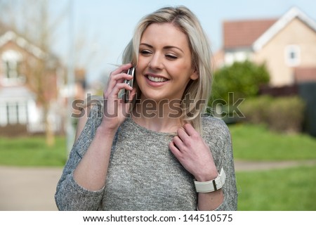Pretty young woman in UK using mobile phone laughing