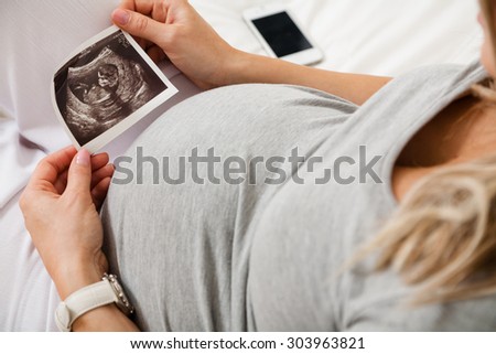 Pregnant woman looking at ultrasound scan of baby, close up of scan
