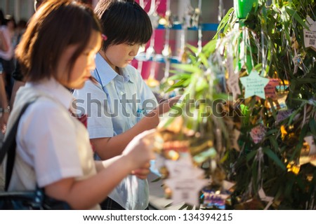 TOKYO - AUGUST 5 : Japanese school girls wishing luck by writting on bamboo leaf in Tokyo, Japan on August 5, 2012. Tokyo is Japan's capital and the world's most populous metropolis.