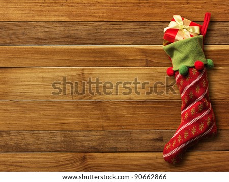 Christmas sock with presents on wood board