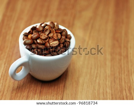Fresh roasted coffee beans in coffee cup on wood board