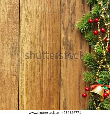 Decorated Christmas tree border on wood paneling with gold baubles and bells, a decorative Xmas gift wrapped in a golden bow, holly and beads with copyspace for your seasonal greeting