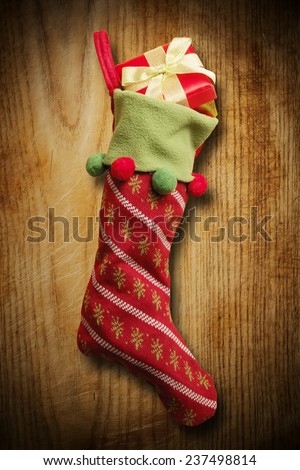Christmas sock with red gift box on wooden background