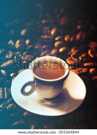 Cup of coffee on a beautiful beans background.Filtered image: cool cross processed vintage effect.
