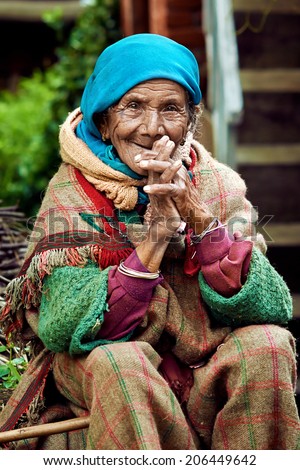 Naggar (Kullu Valley), North India - circa July 2013. Old rural Indian woman sitting in the courtyard of his house. Smiling at the camera.