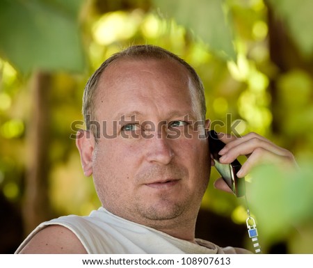 the man speaks by phone sitting in an arbor twined grapes