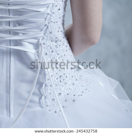 the bride puts on a white dress, a view from a back