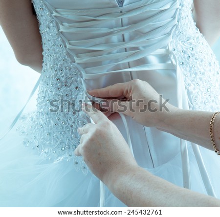 the bride puts on a white dress, a view from a back
