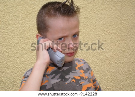 Twelve boy with a fashionable haircut and a telephone in his hand.
