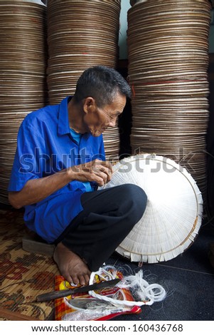 HANOI, VIETNAM - APRIL 21: Vietnamese man sitting sewing hats in a traditional village in Vietnam April 21,2013. Conical hat is a traditional item of ethnic Vietnam