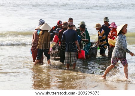 DANANG, VIETNAM - AUGUST 14, 2013: Fishermen sort out their catch on the shore and sell fish to dealers.