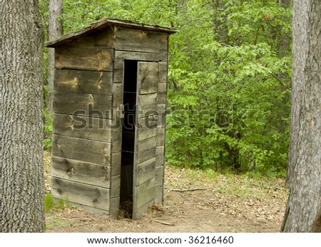 old outhouse with door half open in a woods