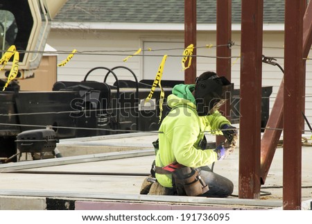 iron worker strikes an arc as he welds beams together in the construction of a building