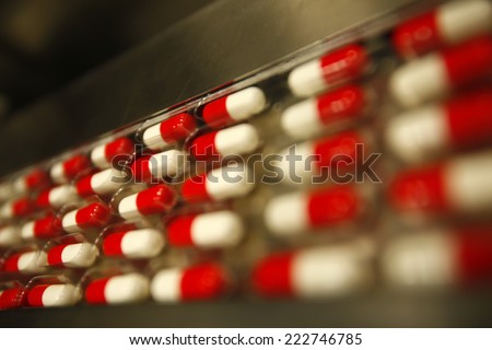 Red and white capsules pills drug production line, tablets coming out of the machine