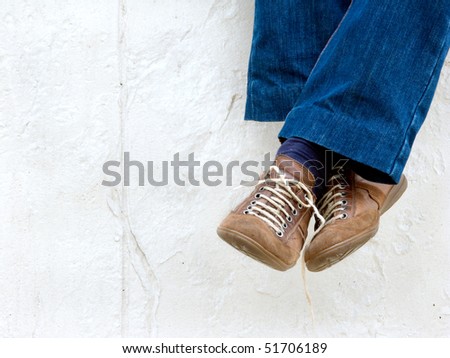 Crossed male legs on the white wall