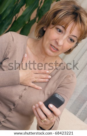 Chocked charming mature woman reading a phone  message.