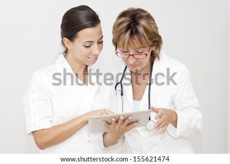 Two female doctors  reviewing health report on the digital tablet.