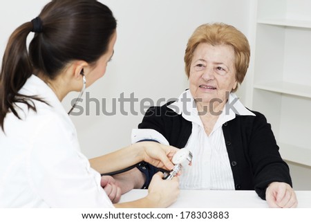 Young nurse checking  blood pressure senior woman .