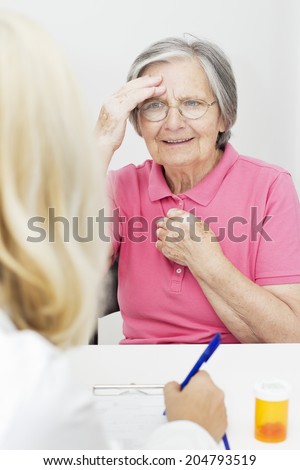 Senior woman touching her head talking with  doctor.