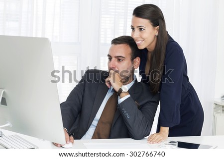 Young businessman and businesswoman  are  working  at  a computer monitor in the office.