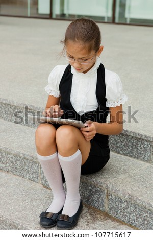 Lovely school girl sitting in the stairs with tablet computer