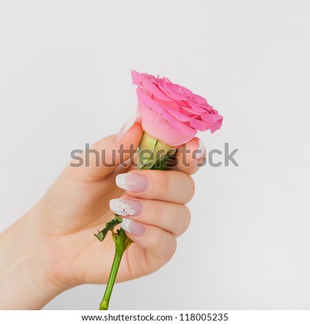 Closeup of beautiful nails with french and pink flower on white background