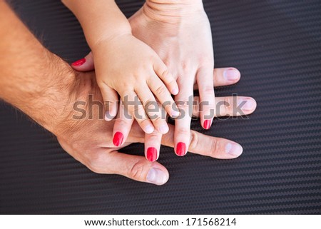 Three hands of the family- baby, mother and father. Concept of family, unity, protection, support and happiness. Focus on infant handle.