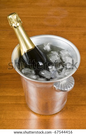 Bottle of Champagne in an Ice Bucket  on a Wooden Table