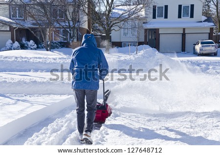 Man Using a Snow Blower Clear his Driveway