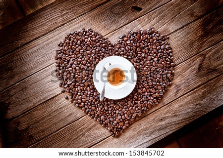 coffee cup on heart form coffee beans, on old wooden background
