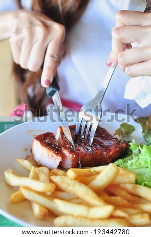 Someone eating grilled steak on white plate