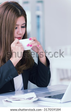 Asia young business woman sitting in a cafe with laptop and coffee, business concept