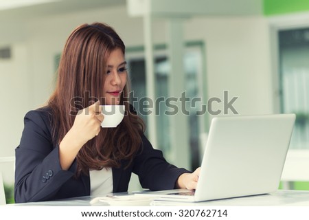 Asia young business woman sitting in a cafe with laptop and coffee, business concept