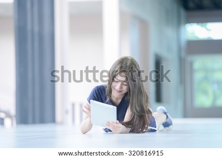 asia girl lying on floor and looking into tablet computer at home