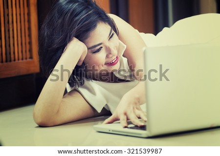 happy asia woman lying on floor with the laptop at home