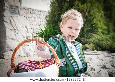Cute boy with Easter basket near an Orthodox church