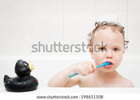 Cute boy brushing teeth in bath