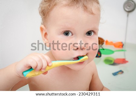 Cute boy brushing teeth in bath