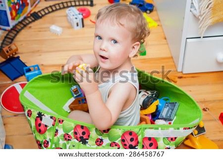 Cute kid sitting in toys box in children room