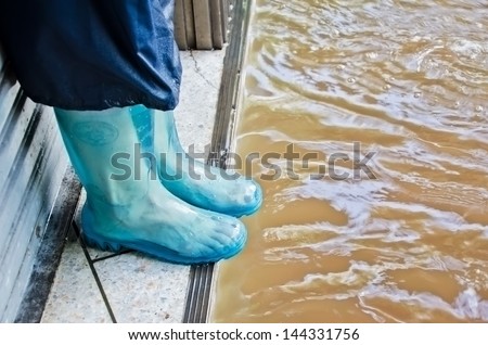 BANGKOK, THAILAND - OCT 29: Unidentified people with rubber boot try to escape from flood during the worst flooding on October 29, 2011 in Bangkok, Thailand