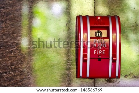 Red Fire alarm on the marble wall with the park outside reflection