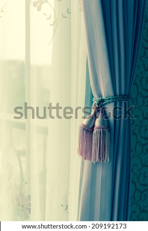 Curtain with curtain tieback at window, selective focus. Processed with vintage style.