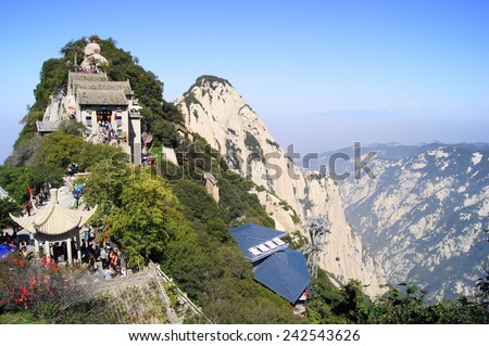 Huashan Mountain North Peak. Scenic rocky forested cliffs. Cable way station, buildings and pavilions on mountain ridge. Crowd of people walking. Sunny autumn day of October 05, 2014. Shaanxi, China.