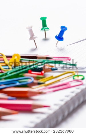 colored pencils and paper clips scattered on a notepad